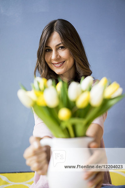 Porträt einer lächelnden Frau mit Tulpenstrauß im Glas