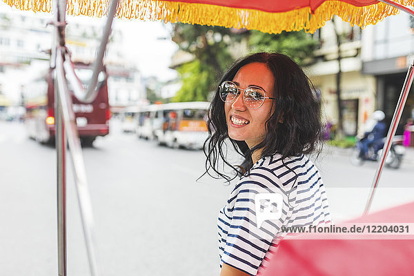 Vietnam  Hanoi  Porträt einer lächelnden jungen Frau auf einer Rikscha in der Stadt