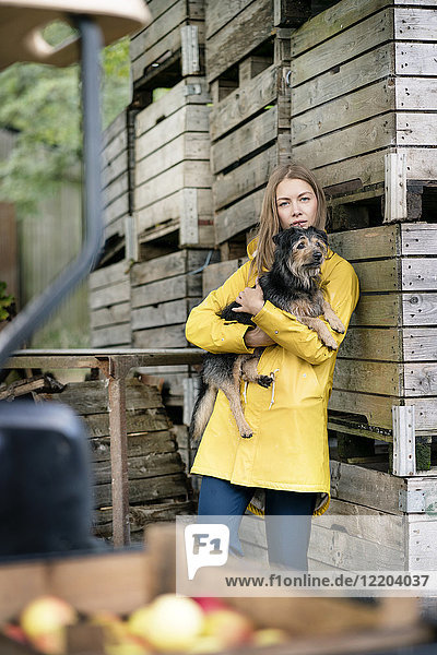 Frau auf einem Bauernhof stehend an Holzkisten mit Hund