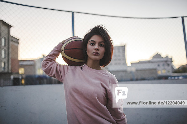 Porträt einer jungen Frau mit Basketball im Freien