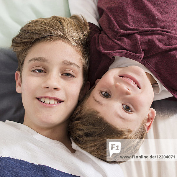 Draufsicht von zwei lächelnden Brüdern auf dem Bett liegend