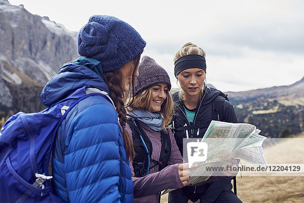 Three young women hiking in the mountains looking at map