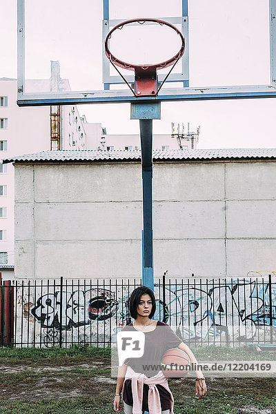 Junge Frau stehend mit Basketball auf dem Außenplatz