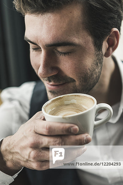 Entspannter junger Mann trinkt eine Tasse Kaffee.