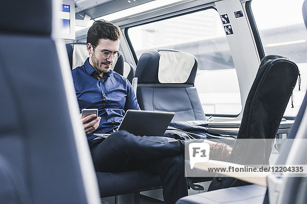 Businessman working in train using laptop