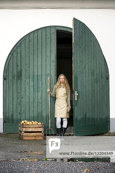 Frau auf einem Bauernhof stehend an einer Kiste mit Äpfeln