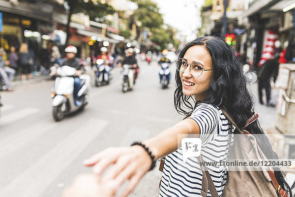 Vietnam  Hanoi  Porträt der lächelnden jungen Frau auf der Straße in der Stadt