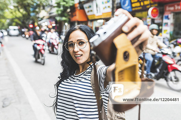Vietnam  Hanoi  junge Frau nimmt einen Selfie mit altmodischer Kamera auf die Straße