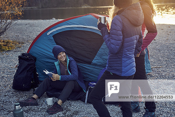 Group of hikers camping at lakeshore at sunset