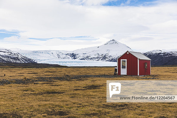 Island  Vik  Scheune im Grünen mit Gletscher im Hintergrund