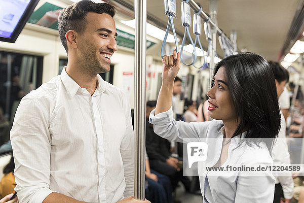 Lächelnder Geschäftsmann und Geschäftsfrau in der U-Bahn