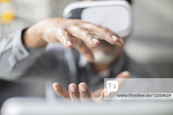 Mann formt mit den Händen mit VR-Brille im Büro