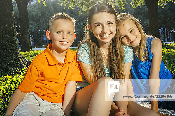 Portrait of smiling Caucasian brother and sisters in park