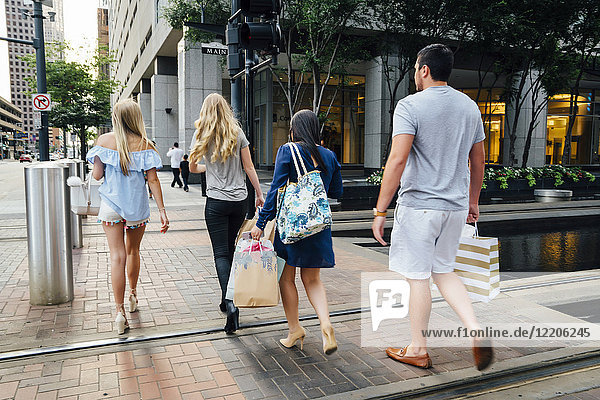Freunde beim Überqueren der Straße in der Stadt mit Einkaufstaschen