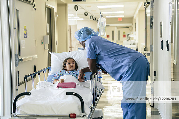 Arzt hält die Hand eines Mädchens auf einer Krankenhausbahre