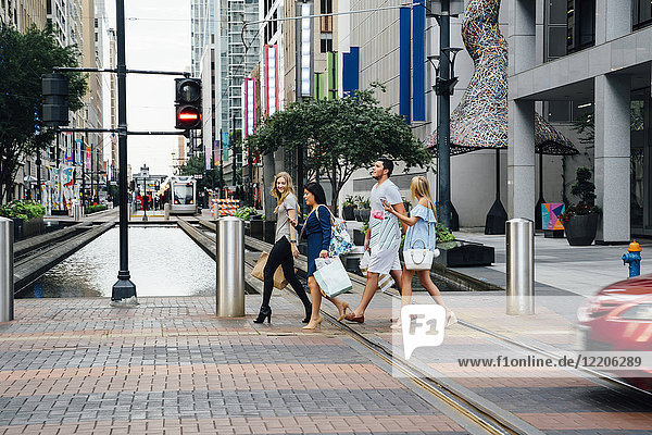 Freunde beim Überqueren der Straße in der Stadt mit Einkaufstaschen
