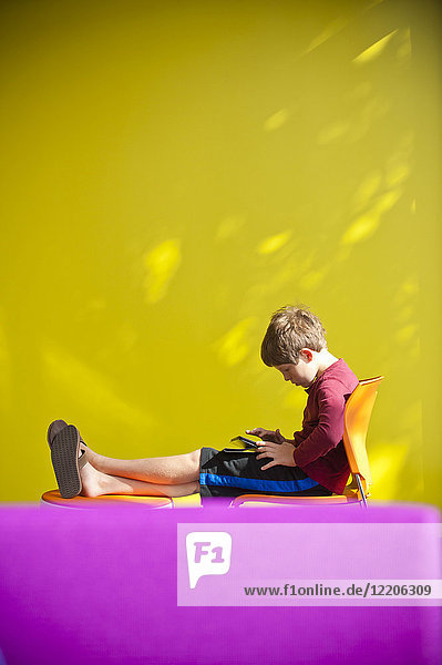 Kaukasischer Junge  der sich entspannt und ein digitales Tablet liest