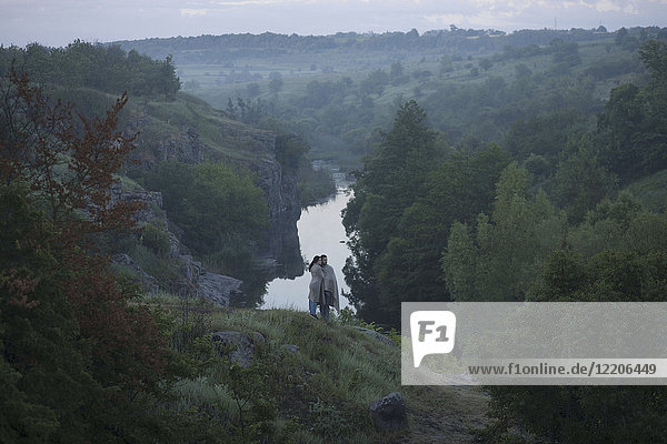 Kaukasisches Paar steht auf einem Hügel über dem Fluss