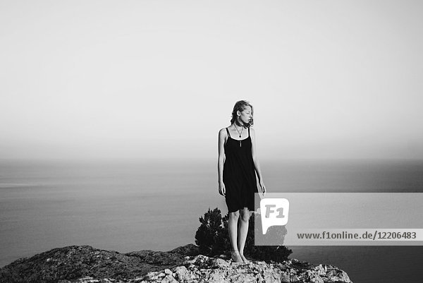 Caucasian woman standing on rock near ocean