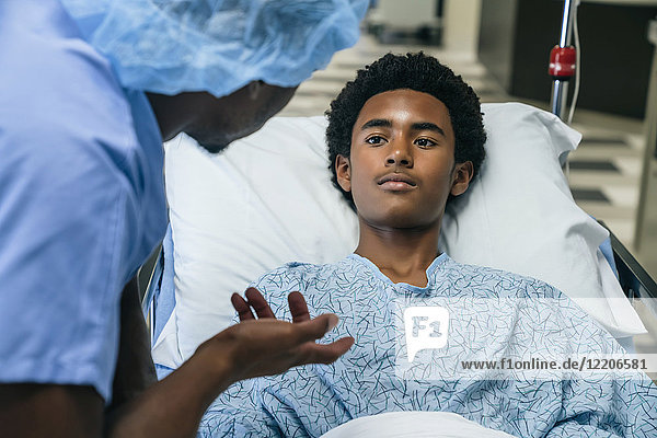 Black doctor talking to boy in hospital bed