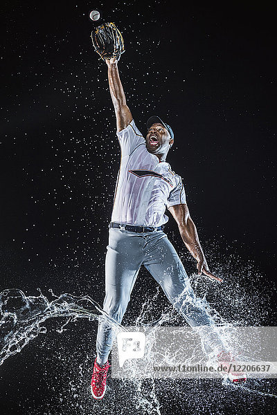 Wasser spritzt auf Beine Schwarzer Baseballspieler fängt Baseball