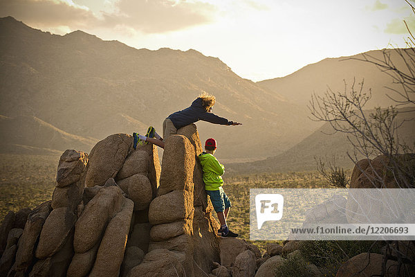 Jungen stehen auf Felsen und bewundern die Wüstenlandschaft