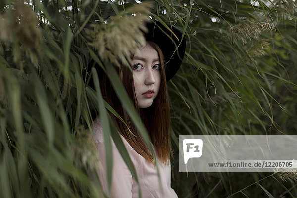 Portrait of serious Asian woman standing in field of tall grass