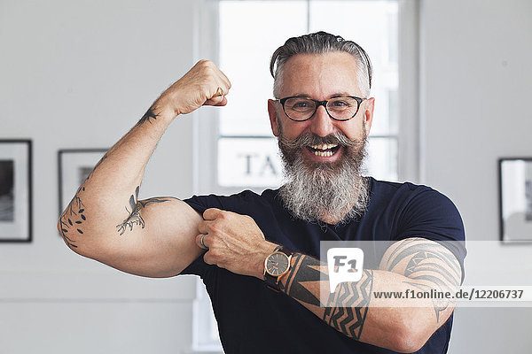 Close up of smiling muscular Caucasian hipster man flexing biceps