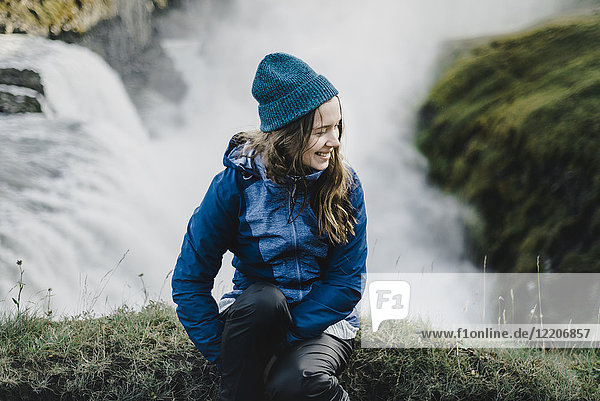 Portrait of smiling Caucasian woman sitting near waterfall