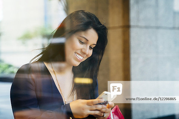 Smiling Hispanic woman texting on cell phone