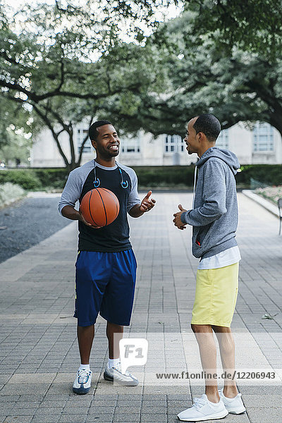 Smiling Black men holding basketball and taking
