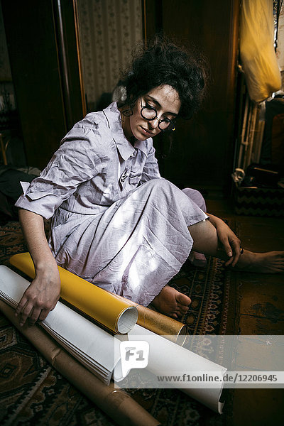 Caucasian woman sitting on floor with rolled up paper