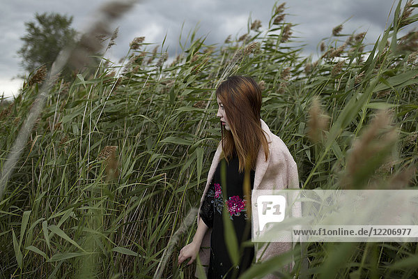 Asian woman standing in field of tall grass