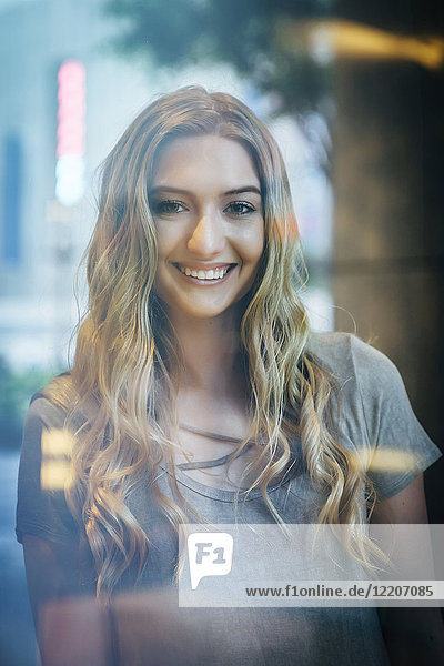 Portrait of smiling Caucasian woman behind window