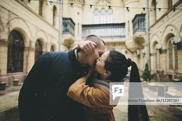 Caucasian couple kissing in courtyard