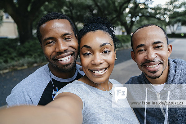 Smiling Black friends posing for cell phone selfie