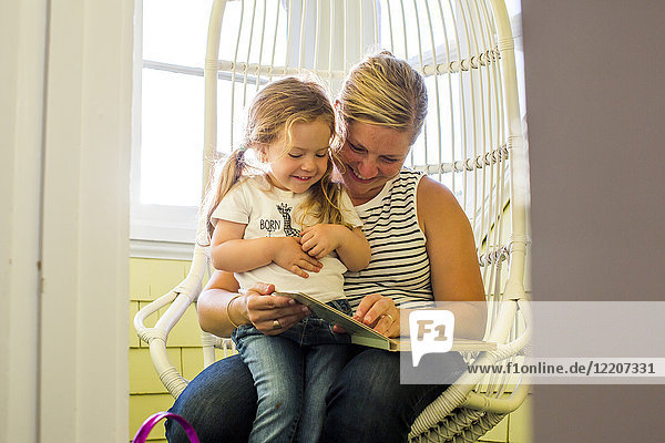 Caucasian mother reading book to daughter on lap