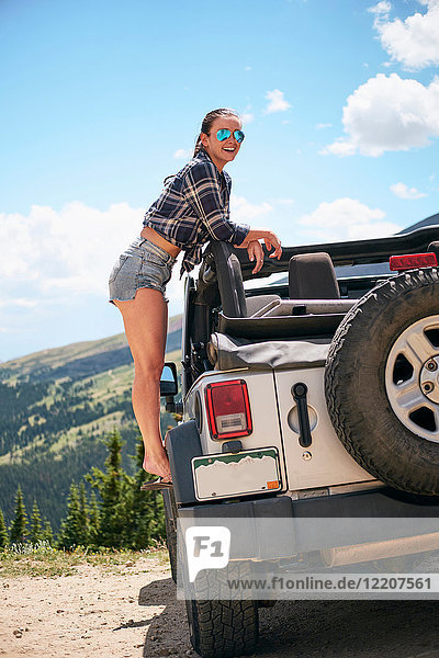 Junge Frau auf Autoreise  die vom geparkten Geländewagen auf die Berge schaut  Breckenridge  Colorado  USA