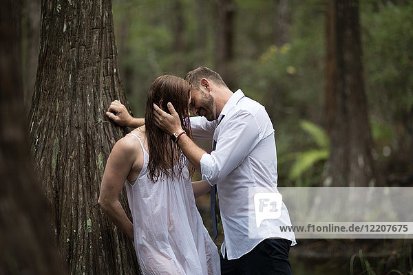Paar  das sich gegen einen Baum küsst