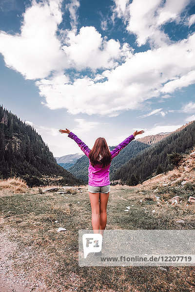 Junge Frau mit offenen Armen mit Blick über das Bergtal  Draja  Vaslui  Rumänien  Rückansicht