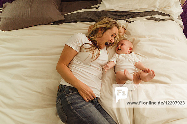 Draufsicht von Frau und Baby-Tochter im Bett liegend