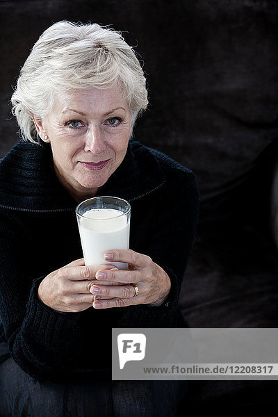 Porträt einer älteren Frau  die ein Glas Milch hält