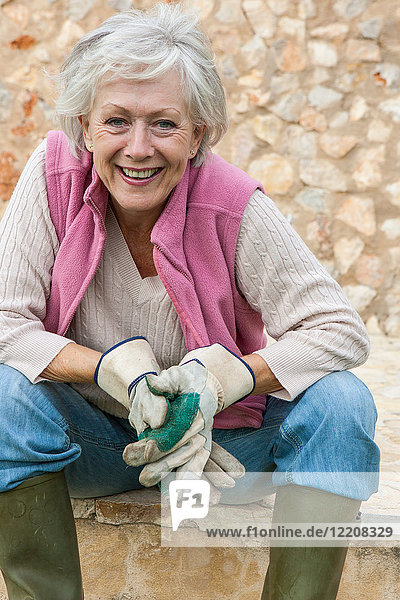 Porträt einer älteren Frau im Freien  die Gartenhandschuhe trägt