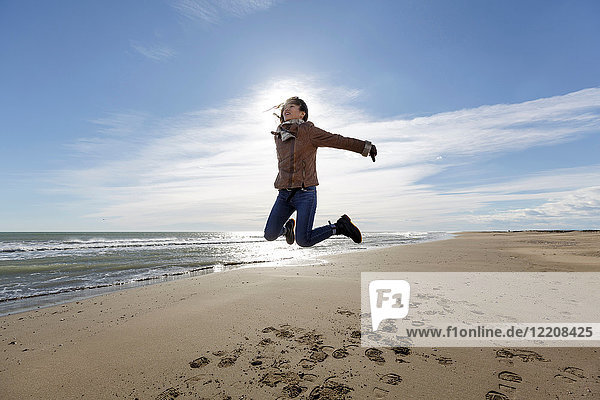 Junge Frau springt am Strand in die Luft  Tarragona  Katalonien  Spanien