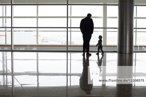 Father and son beside window at airport  Alberta  Canada