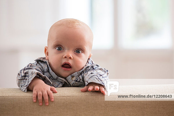 Porträt eines kleinen Jungen  der auf ein Sofa klettert