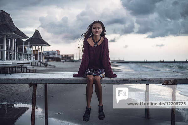 Portrait of young woman sitting on pier at dusk  Odessa Oblast  Ukraine