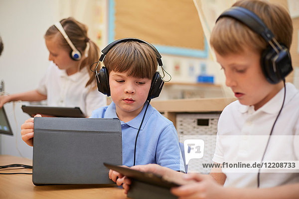 Schülerinnen und Schüler  die in der Grundschule im Unterricht Kopfhörer hören