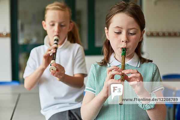 Schulmädchen spielen Blockflöten im Klassenzimmer der Grundschule