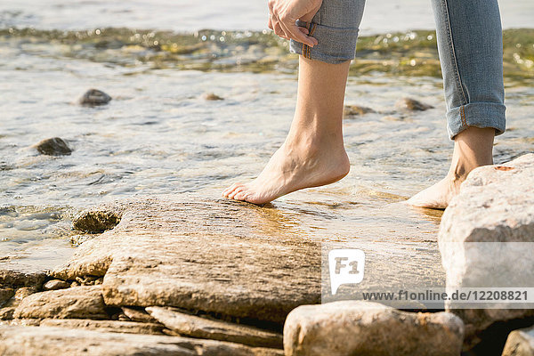 Cropped view of woman barefoot on rocks